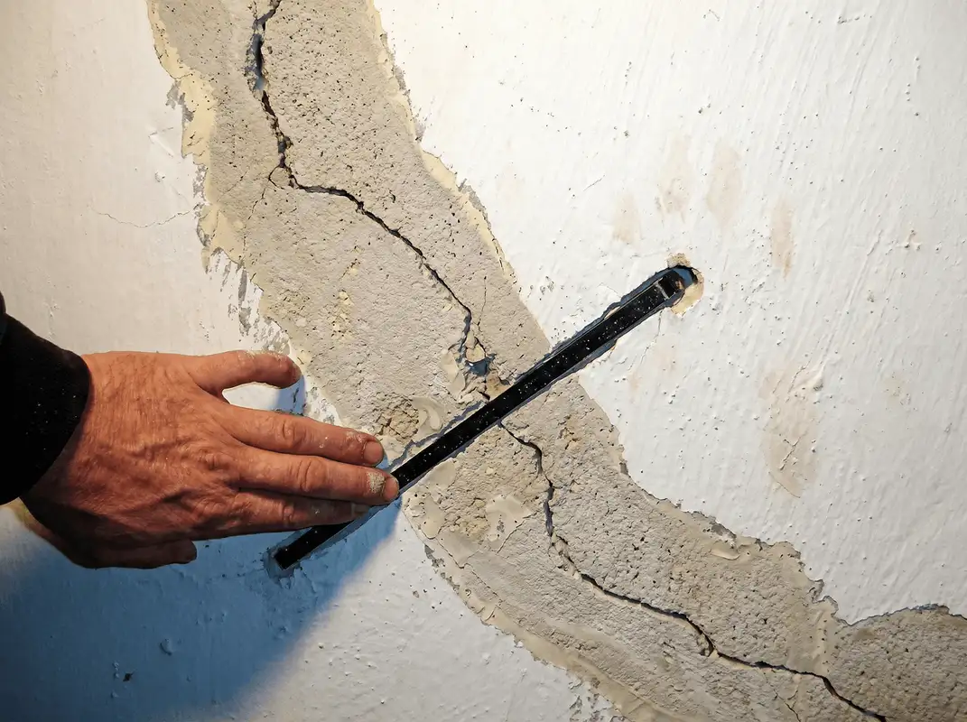 A wall with a large crack is being inspected by a professional in New Haven, CT