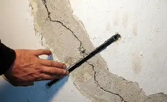 A wall with a large crack is being inspected by a professional in New Haven, CT